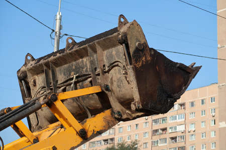Excavator bucket on the background of a residential buildingの写真素材
