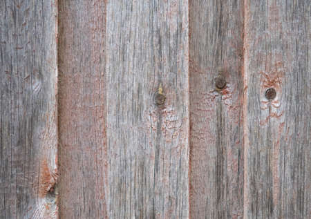 Old wooden fence boards with knots with traces of red paint, backgroundの写真素材