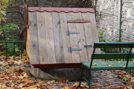Wooden roof of a well and a bench, fallen leaves, autumnの写真素材