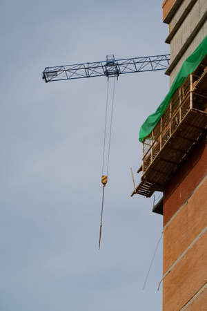 Scaffolding on a high-rise building under construction and a crane boomの写真素材