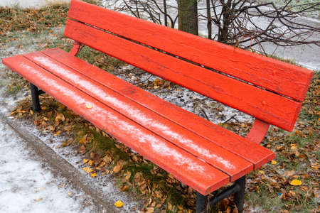 Red wooden park bench covered with thin iceの写真素材