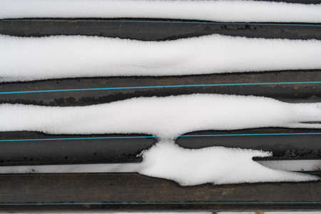 Snow covered construction hoses with blue stripe, winter backgroundの写真素材
