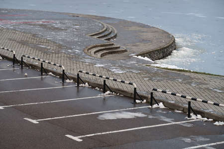 Parking near the stone embankment by the ice-covered pond, cloudy, winterの写真素材