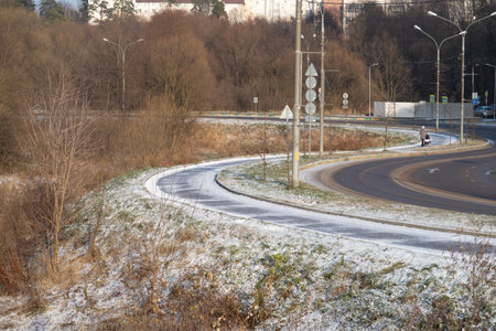 S shaped zigzag of asphalt road and sidewalk among bushes covered with first snowの写真素材