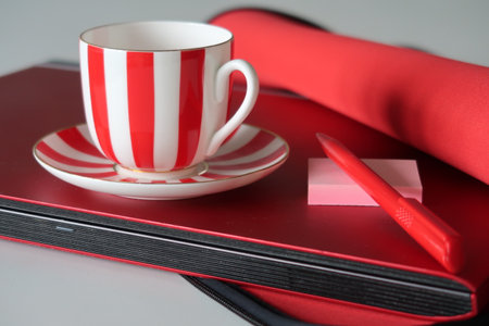 Cup, pen and stickers on the lid of a red notebook half taken out of the case, freelancerの写真素材