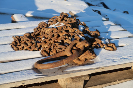 Massive iron rusty chain on a wooden pallet, snowの写真素材