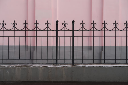 Openwork metal fence on the background of a pink wallの写真素材