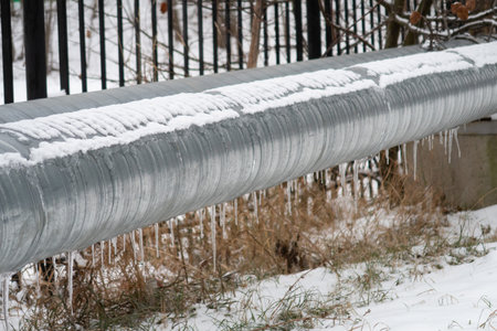 Snow icicles on a metal pipe of a heating mainの写真素材