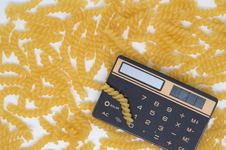 Calculator on the background of pasta spirals, calculating the calorie content of a diet