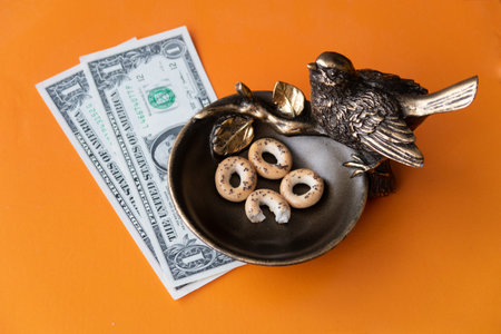 A bronze bird pecks at the steering wheel and brings good luck in business, there a few dollars next to itの写真素材