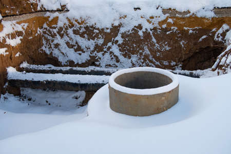 A trench with pipes carrying heat for heating is covered with snow, background