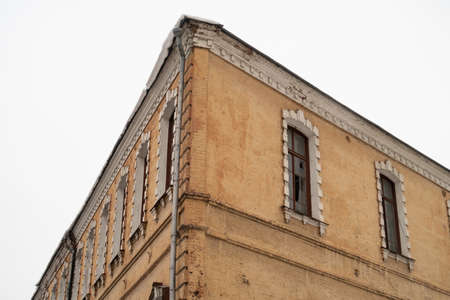 Corner of an old brick abandoned house, red bricks, cornices, windows and frames