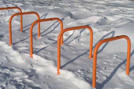Bicycle parking at the entrance to the park covered with snow, background