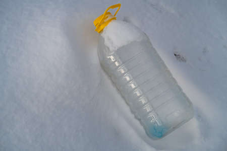 Plastic bottle with the remnants of antifreeze lies on the snow, ecology, backgroundの写真素材