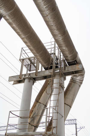 Bending of two thick pipes of the heating system on a high support with a metal staircase,...