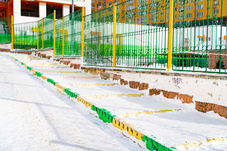 Cleared footpath, fence and border in yellow and green colors, city backgroundの写真素材