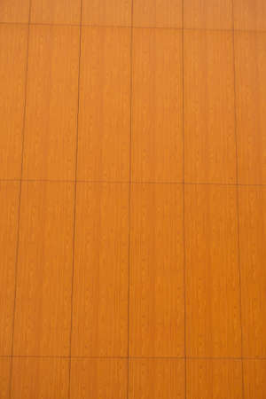 The wall of the building is covered with orange plastic panels with a dull pattern, backgroundの写真素材