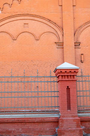 Metal fence with brick pillar on a red brick wall background, backgroundの写真素材