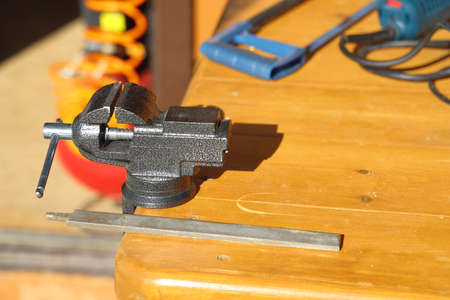 Small locksmith vise and file on a wooden work table in the country