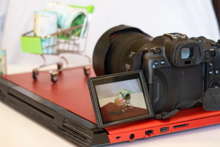 Toy cart with banknotes and a camera on the laptop lid, photo session for photo stocksの写真素材