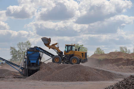 A forklift loads pebbles into a sorting machine in a quarry, Samara region, August, 2021