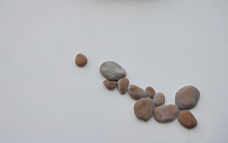 Smooth stones on vertical white wall, wall decoration, backgroundの写真素材