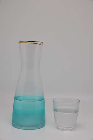 Transparent jug with water and glass glass with water, background in pastel colorsの写真素材