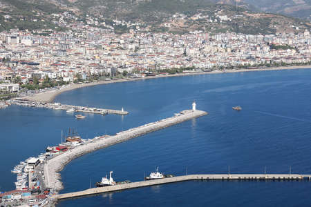 Port with ships and piers against the background of residential buildings and mountains, beautiful Mediterranean sea background, Alanya November 2021.のeditorial素材
