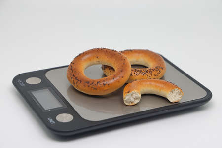 Bagels with poppy seeds are on the kitchen scales, diet and extra calories.の写真素材
