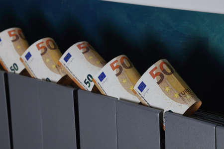 Fifty euro banknotes inserted into the slots of the heating radiator, the rise in the cost of heat, the fuel crisis in Europe.の写真素材
