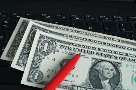 American banknotes and red pen on keyboard, writing custom texts, copywriter, freelancer.の写真素材