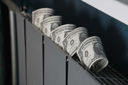 Dollar bills inserted into the radiator slots of the heating system, the increase in the cost of heat, fuel crisis, utility bills.の写真素材