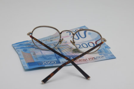 A pair of round glasses with a banknote inside. Economic concept.