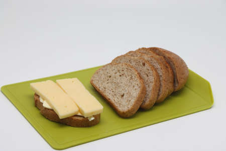 A sandwich with cheese and butter. Bread with bran sliced into lobes on a cutting board.の写真素材