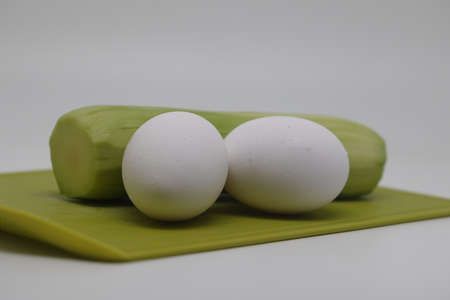 Zucchini and two raw chicken eggs lie on a cutting boardの写真素材