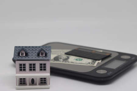 Toy house and banknotes lie on kitchen electronic scales, real estate purchase.の写真素材