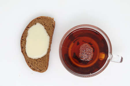Sandwich from muffin with condensed milk in plate, tea and spoon on wooden table. Top view.