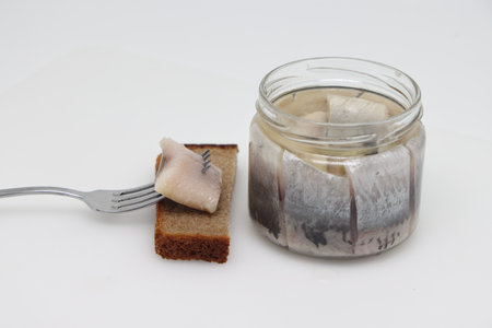 Pieces of salted herring on fork on white backgrod.の写真素材