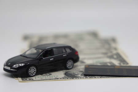 A toy car and banknotes lie on a kitchen electronic scale next to a calculator, the cost of...