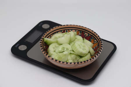 cucumber slices in a painted ceramic mascot, kitchen scales, calorie counting.の写真素材
