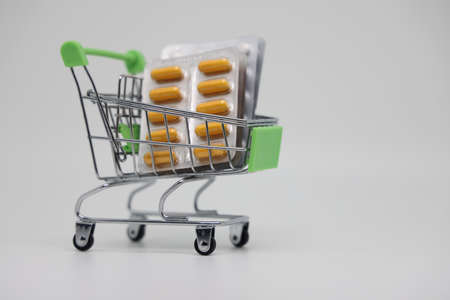 A supermarket trolley full of blister pills, a lot of pills in a wheelbarrow. Concept: home delivery of medicines.Empty space, a place for text, poster, board. Medical blue backgroundの写真素材