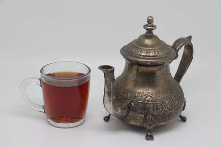 Antique metal teapot on a white background. Close up of an old Arabic teapot. A cup of tea