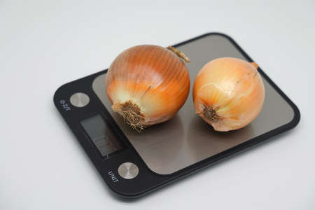Beautiful strong white onion heads on an electronic kitchen scale. Healthy food, diet
