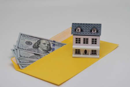 Banknotes in a yellow envelope and a toy house, funds for the purchase of real estateの写真素材