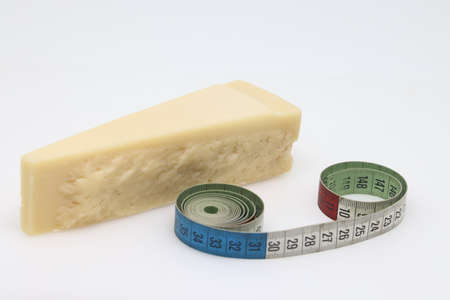 a piece of cheese and a tailor meter isolated on a light background, proper nutrition, counting...