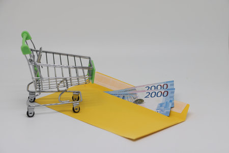Trolley from the supermarket and banknotes in an envelope, shopping in retail chainsの写真素材