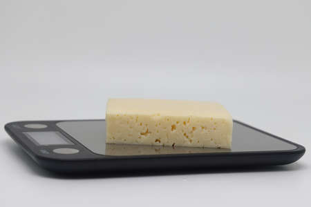 A piece of cheese on the scales. Weight loss, diet and weight control. Still life with healthy food...