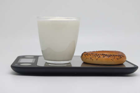 A glass of thick kefir on the scales. Weight loss, diet and weight control. Still life with healthy food and scales. Health food. The concept of a healthy lifestyle. weight control during self isolationの写真素材