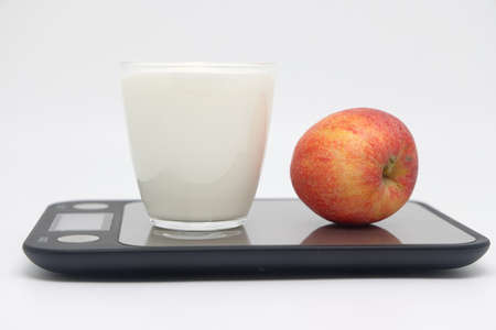 A glass of thick kefir on the scales. Weight loss, diet and weight control. Still life with healthy...