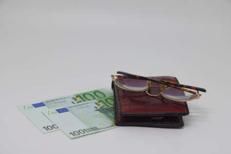 Brown wallet with banknotes and glasses. brown frame. Symbol of accounting and family finance planningの写真素材
